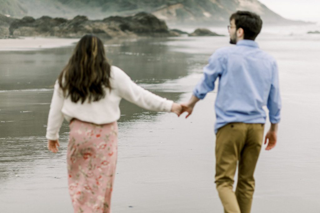 a couple holding hands on the oregon coast