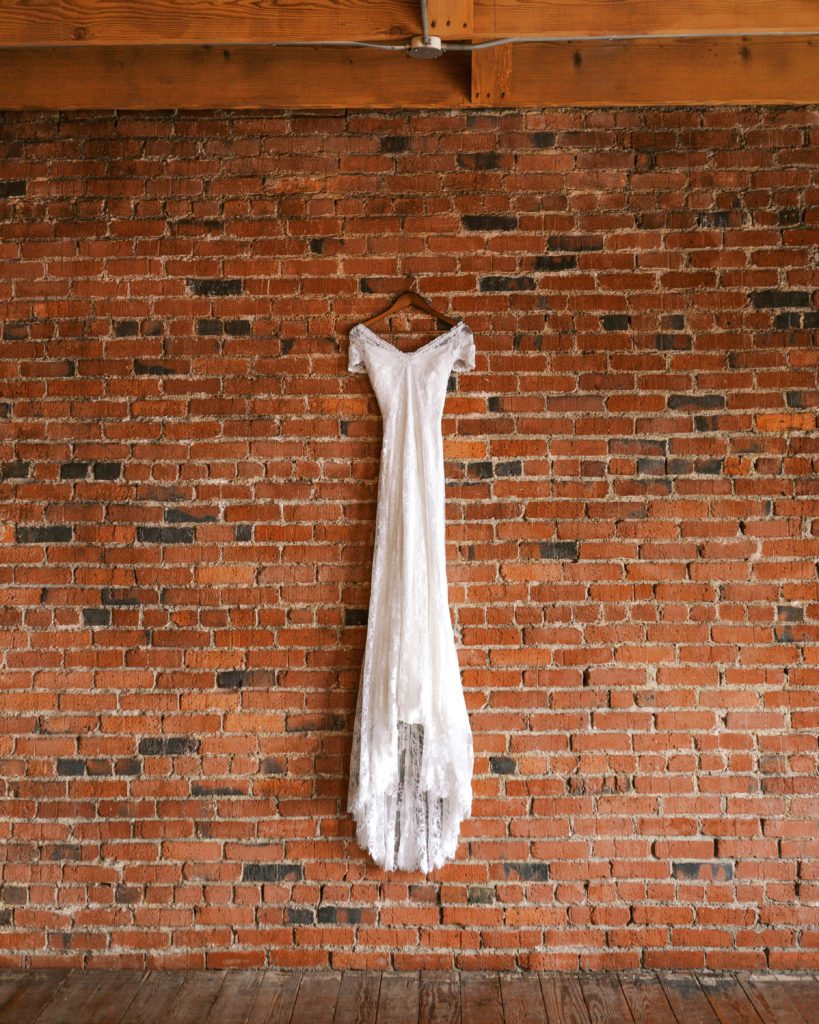 A wedding dress hangs on a brick wall at the loft in chehalis washington