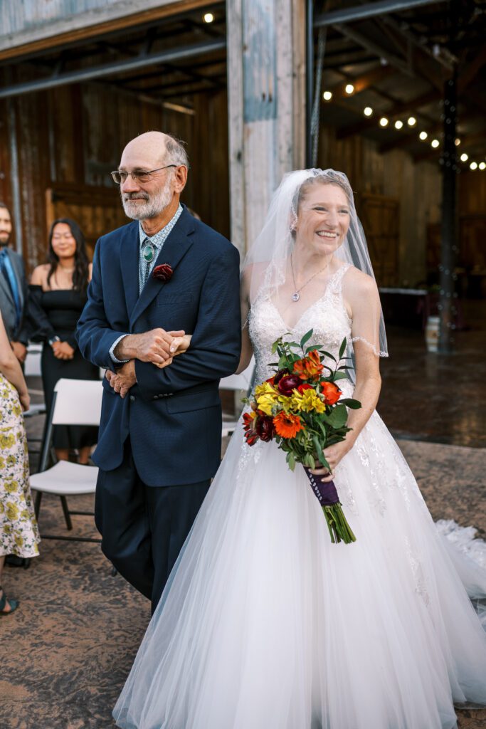 a bride and her father walking down the aisle at spire mountain cellars