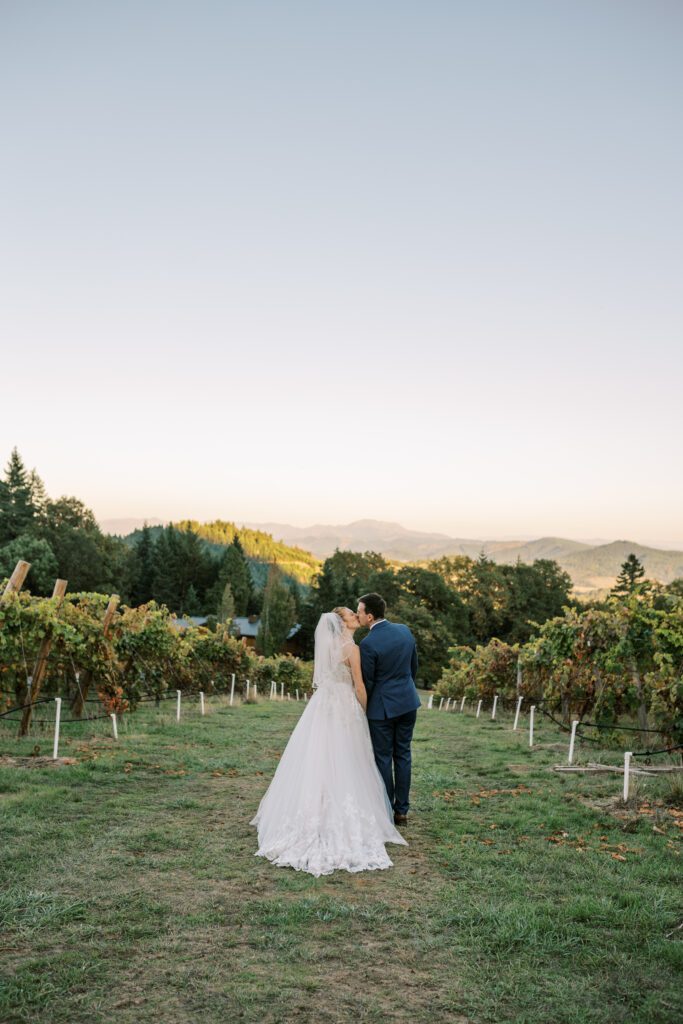 newlyweds kiss in the vineyard at sunset at spire mountain cellars